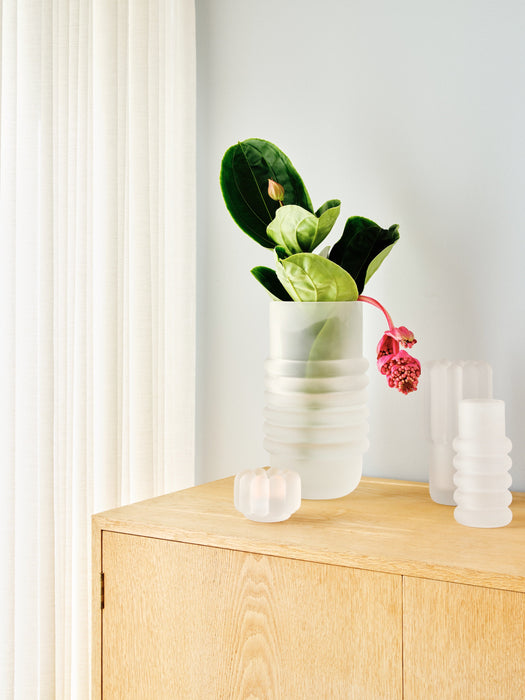 Press Stem Vase 磨砂玻璃花瓶（高款）和其他 Press 產品擺放在淺色木質櫃子上，背景有白色紗質窗簾，營造柔和光線氛圍。